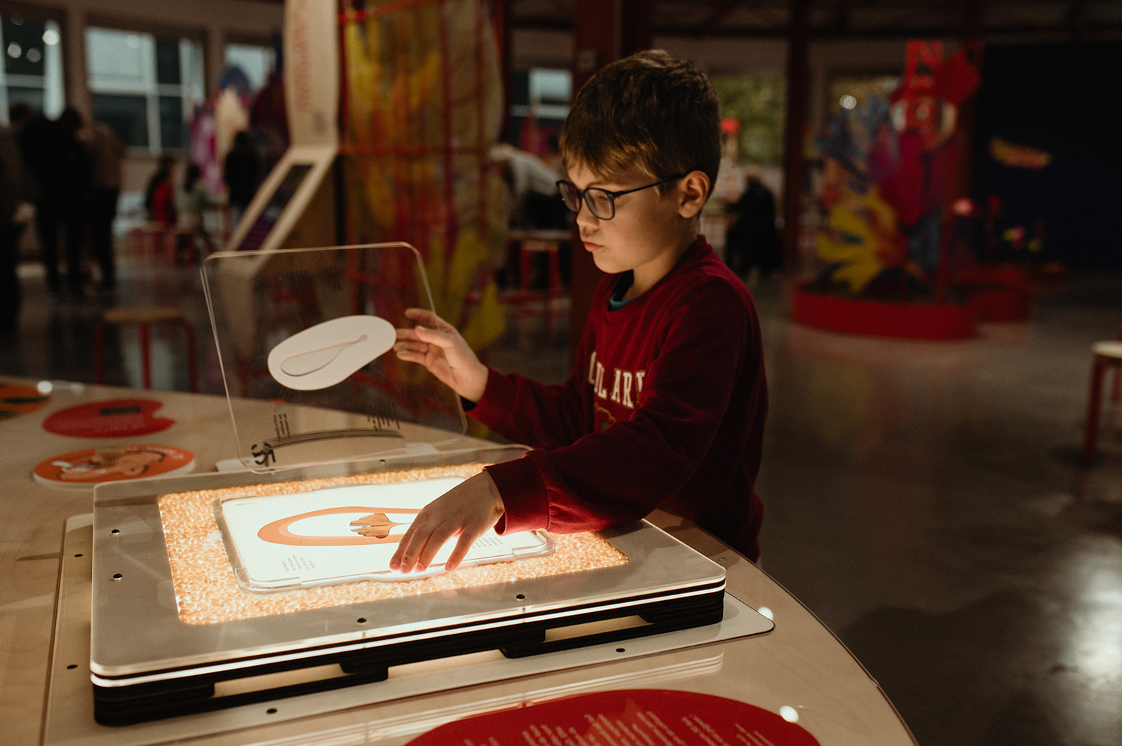 Photo d'un enfant posant un poid sur une balance lors d'une activité ludique de l'exposition graines